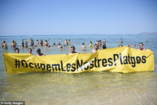 Члены ассоциации Mallorca Platja Tour протестуют против перенасыщения туристами с плакатом с надписью: «Давайте оккупируем наши пляжи!» на пляже Пальма-де-Майорка 11 августа 2024 года на Майорке, Испания.